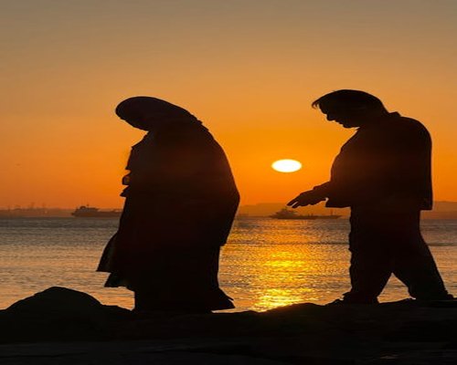 person walking on beach at sunset